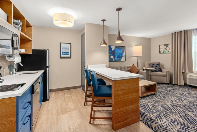 Extended stay hotel suite dining area with dimmable LED pendant lights over kitchen island