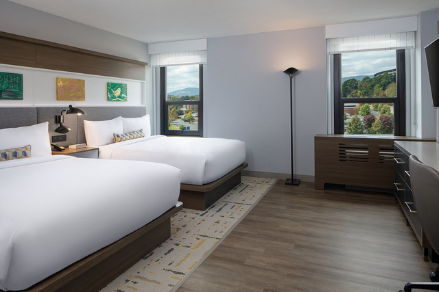 Queen bed guestroom featuring energy efficient LED ceiling lights and task lighting