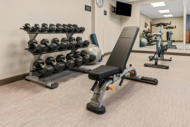 Extended stay hotel gym featuring bright LED ceiling lights and free weight training area